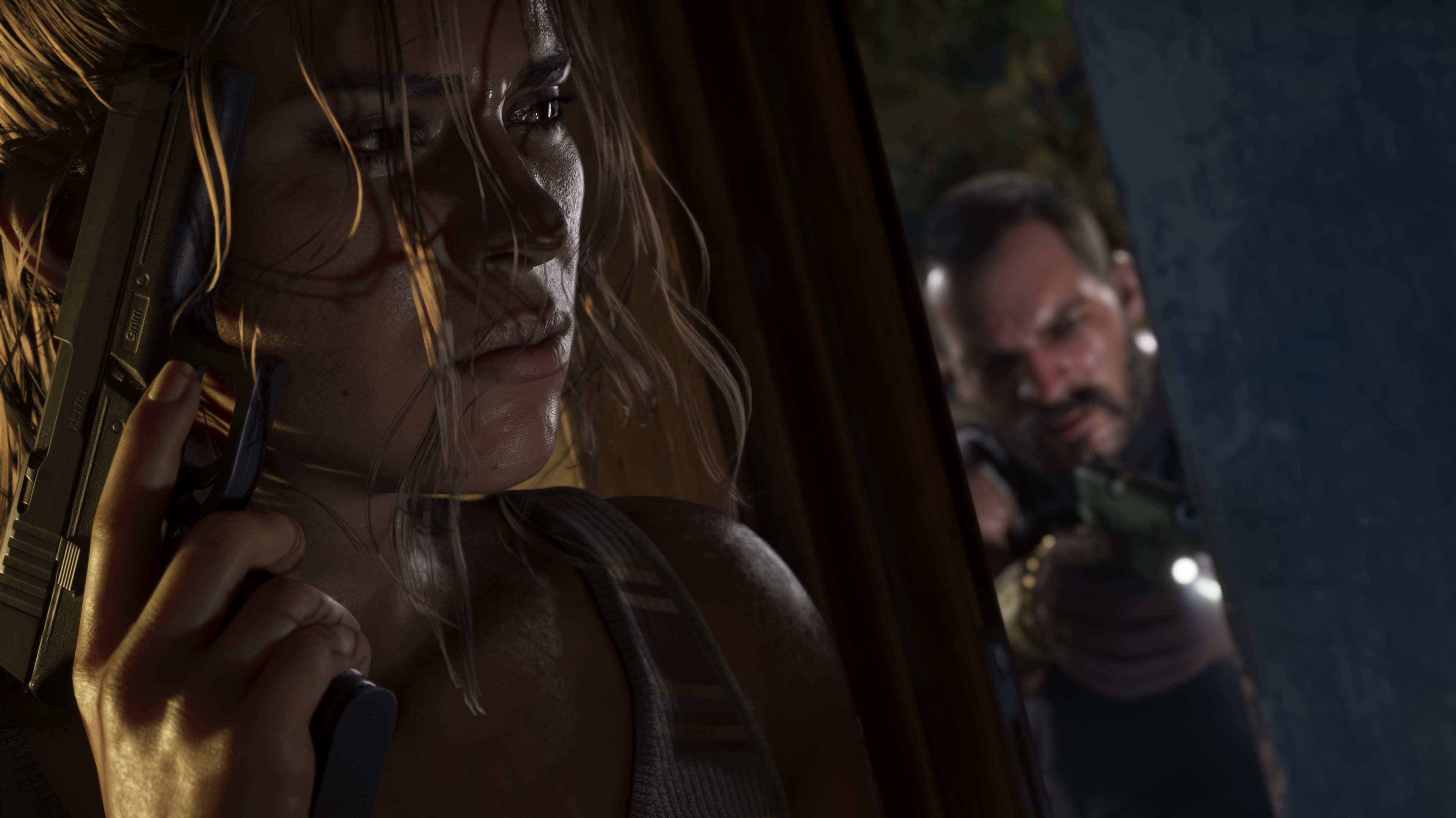Lucia takes aim with a rifle in a dark interior as her partner covers behind